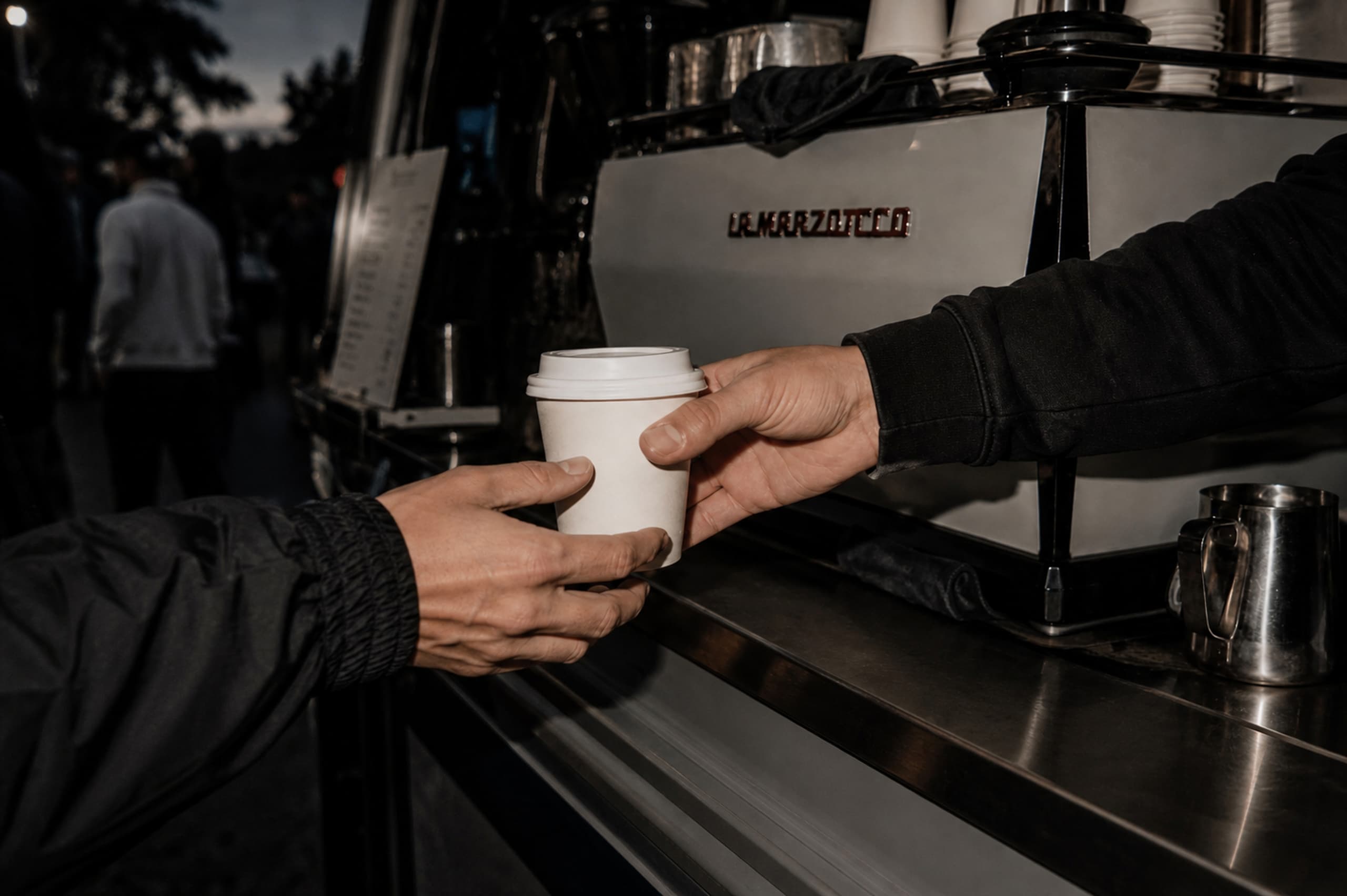 A coffee cup passed from one hand to another at the MOKOKO cart.