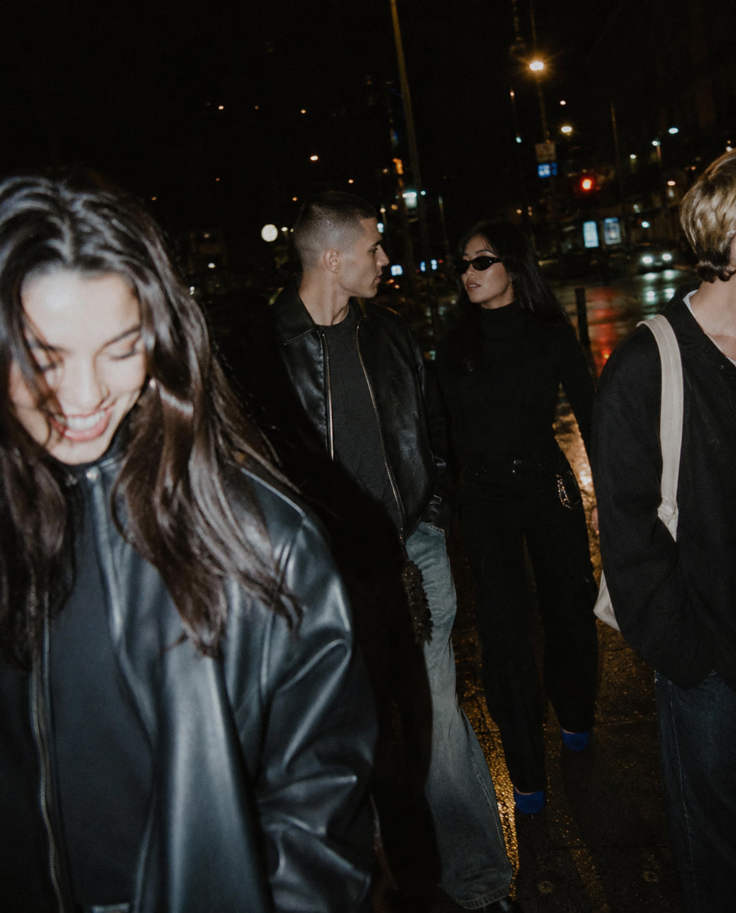Friends walking through the city at night, caught mid-conversation.