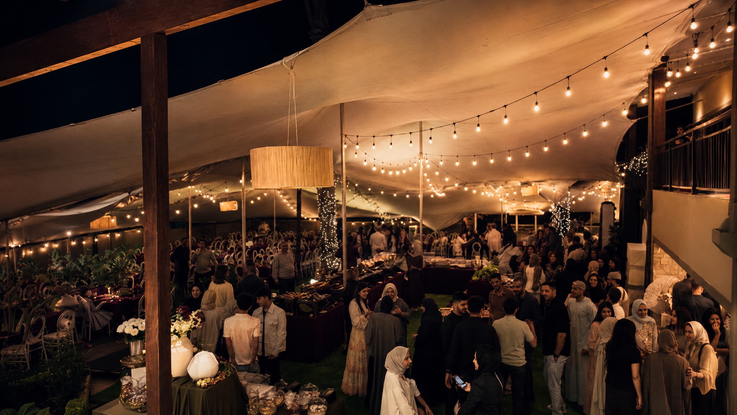 An evening gathering under a canvas awning strung with lights — people everywhere, coffee somewhere among them.