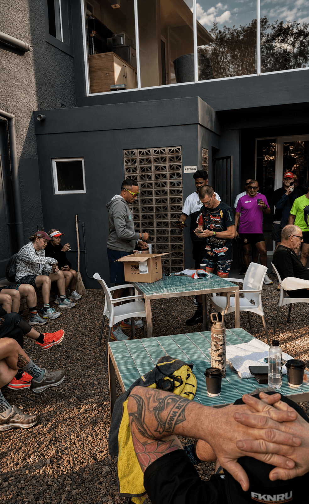 Runners gathered outside after a run — coffee, phones, conversation.